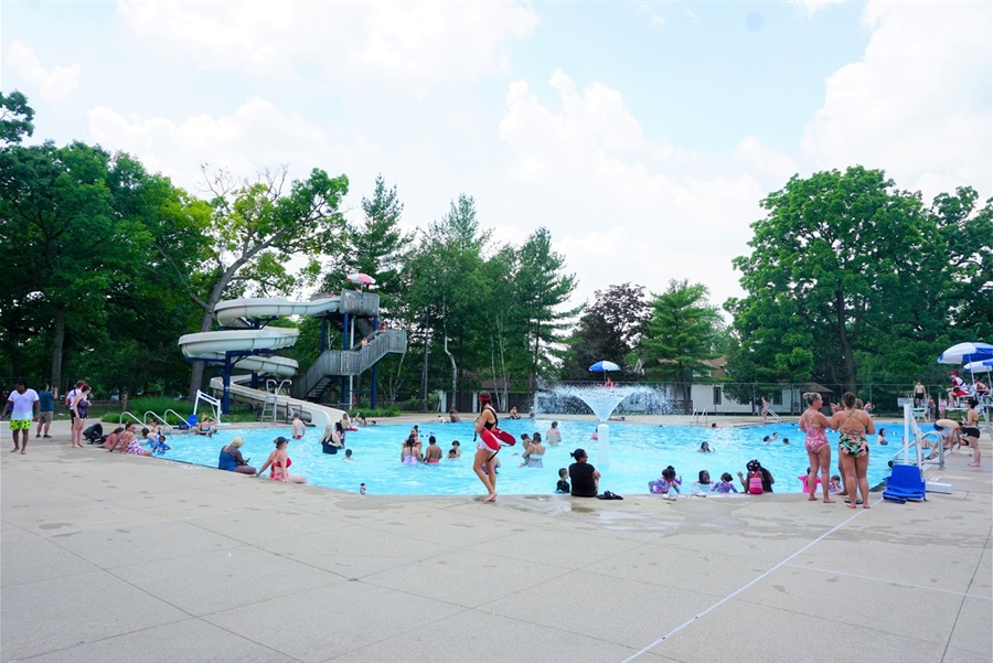People enjoy Briggs Park Pool with a spray fountain and slide.