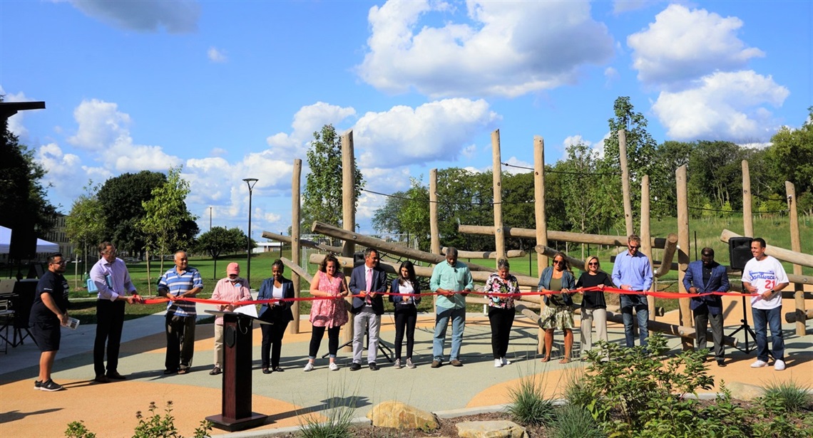 City leaders and neighborhood residents cutting a ribbon at a grand reopening ceremony at Roberto Clemente Park