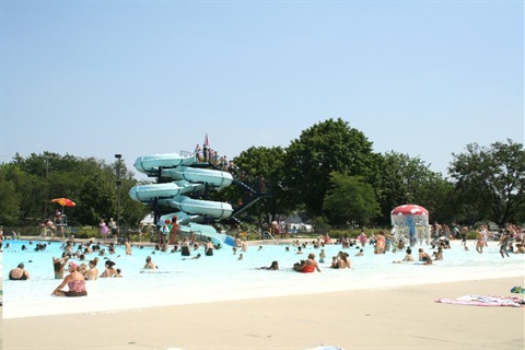 wide shot view of people swimming in a pool with a waterslide